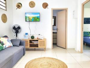 a living room with a couch and a tv on the wall at Logement de charme, au soleil et proche de la mer in Moorea
