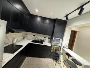 a kitchen with black cabinets and white counters at Charming Apartment - Near Cairo Airport in Cairo +103 photos