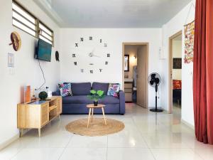 sala de estar con sofá azul y reloj en la pared en Une pause au soleil et proche de la mer, en Moorea
