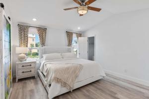 a white bedroom with a bed and a ceiling fan at Blue Beak Bungalow in Pensacola
