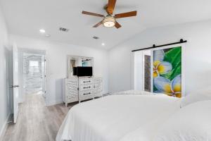 a white bedroom with a bed and a ceiling fan at Blue Beak Bungalow in Pensacola