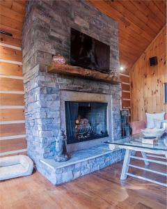 a living room with a stone fireplace with a tv at Luxurious Mountain Retreat with Hot Tub Jacuzzi Suite & Wood-Burning Fireplace - 10 Min to Boone in Rominger