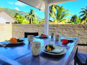 a blue table with plates of food on it at Charmant logement avec accès privé à la plage in Moorea