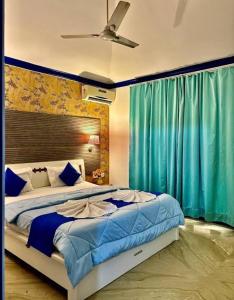 a bedroom with a large bed with blue curtains at Sky Bloom Villa in Nagoa-Bardez