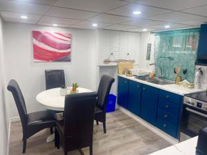a kitchen with blue cabinets and a table with chairs at Spacious Basement Lower Suite 3BR Home Stay 1 King 2 Queen Beds 2 Car Parkings FIFA 2026 in Pickering