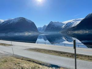 een weg naast een meer met besneeuwde bergen bij JOlster apartaments in Årdal