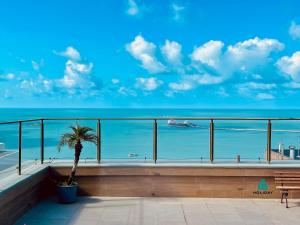 een balkon met uitzicht op de oceaan en een palmboom bij Scala Residenza By Holiday Stays in Fortaleza