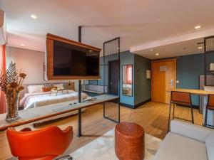 a living room with a large flat screen tv at Manhattan Porto Alegre by Mercure - 5 minutos do Hospital Moinhos de Vento in Porto Alegre +132 photos