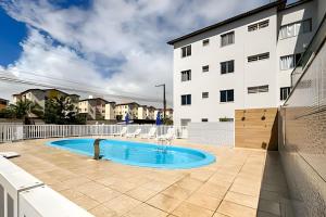 a swimming pool in front of a building at Apto com AR, 3/4 em condomínio com piscina e lazer in Aracaju