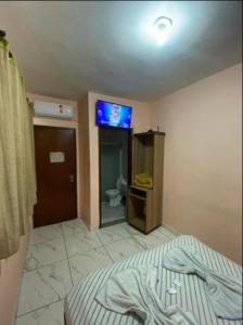 a bedroom with a television and a bathroom with a toilet at Pousada Recanto do Brás in Sao Paulo