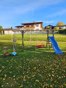 a playground with a slide and swings in a field at Ferienwohnung Ott in Halblech