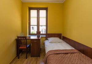 a bedroom with a bed and a desk and a window at Apartament Stare Miasto 1 in Elblag