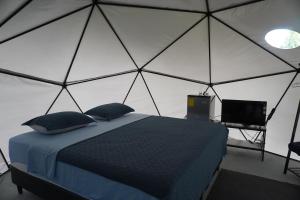 a bedroom with a tent with a bed and a television at Osaglamping in Palmar Norte