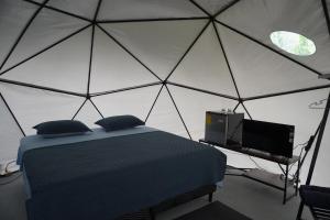 a bedroom with a tent with a bed and a tv at Osaglamping in Palmar Norte
