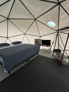 a bedroom with a tent with a bed and a tv at Osaglamping in Palmar Norte