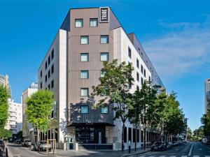 a tall building on a city street with trees at Tribe Paris La Defense Esplanade in Courbevoie