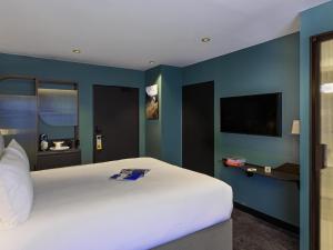 a bedroom with a white bed and a blue wall at Tribe Paris La Defense Esplanade in Courbevoie +60 photos