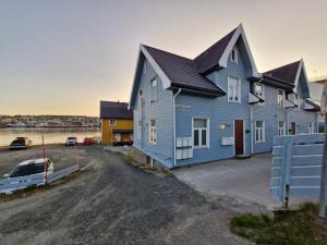 a blue house with a car parked in a lot at Leilighet sentralt i Tromsdalen in Trondalen