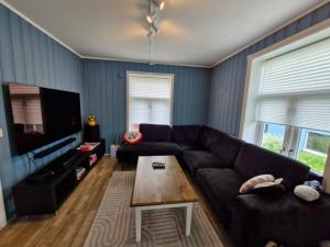 a living room with a black couch and a coffee table at Leilighet sentralt i Tromsdalen in Trondalen