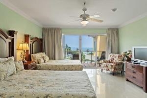 a bedroom with two beds and a television and a balcony at Beachfront - Best View 2BR condo - E422-2 in Palm-Eagle Beach +55 photos