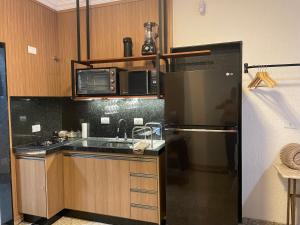 a kitchen with a black refrigerator and a sink at Belíssimo Estudio Stella Maris in Andradina