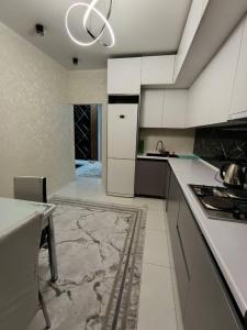 a kitchen with white cabinets and a table and a chandelier at Urban oasis in Bishkek