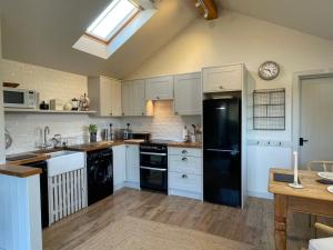 a kitchen with white cabinets and a black refrigerator at 1 Bed in Ullswater 94068 in Watermillock