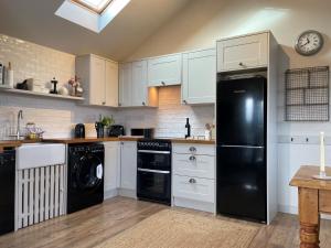 a kitchen with white cabinets and a black refrigerator at 1 Bed in Ullswater 94068 in Watermillock +12 photos