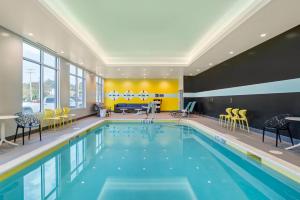 a pool in a hotel with yellow chairs and tables at Tru By Hilton Gastonia in Gastonia