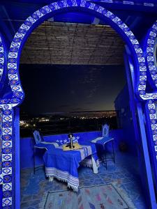 ein blaues Zimmer mit Tisch und Blick auf die Stadt in der Unterkunft DAR AMRANi in Chefchaouen + 7 Fotos