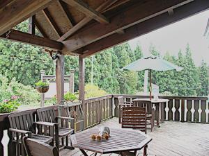 une terrasse en bois avec des tables, des chaises et un parasol dans l'établissement Minamiuonuma - Hotel - Vacation STAY 23110v, à Myōgasawa