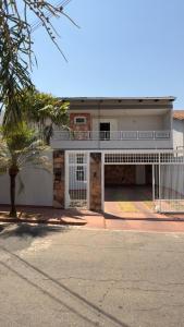 a white house with a gate and a palm tree at Casa da Rosa in Goiânia