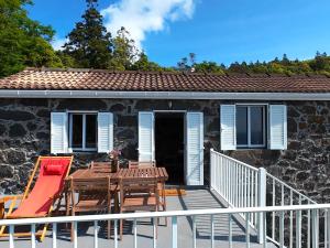 a deck with a table and chairs on a house at Casa das Duas Ribeiras in Lajes do Pico