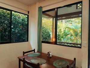 a dining room with a table and two windows at Casa Farolito Rodeada de naturaleza y paz in Hone Creek +2 photos