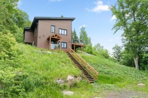 a house on a hill with stairs leading up to it at Laurentides Scandinavian Chalet with Jacuzzi and Lake in Sainte-Lucie-de-Doncaster