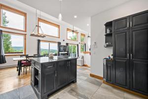 a kitchen with black cabinets and a dining room at Laurentides Scandinavian Chalet with Jacuzzi and Lake in Sainte-Lucie-de-Doncaster