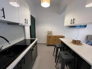 Una cocina con gabinetes blancos y una encimera con taburetes. en Loutraki's Seaside Serenity, 2 BDRM apartment, en Loutraki