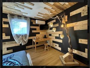 a room with wooden walls and a desk with a window at le valhalla odin in Forges-les-Eaux