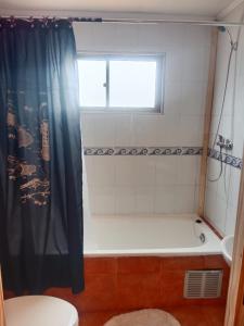 ein Badezimmer mit Badewanne und Toilette und einem Fenster in der Unterkunft Cabaña en Playa Totoralillo in Totoralillo