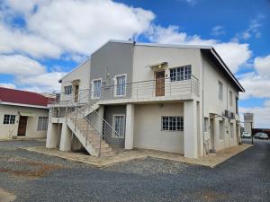 a white building with a staircase on the side of it at Booth Suite Hotel Mafikeng in Mahikeng