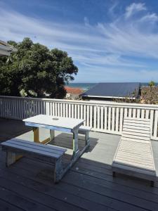 a picnic table and two benches on a deck at Magna Apartment in Jeffreys Bay