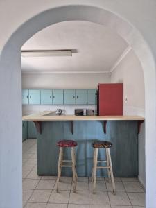a kitchen with a counter and two stools at Magna Apartment in Jeffreys Bay