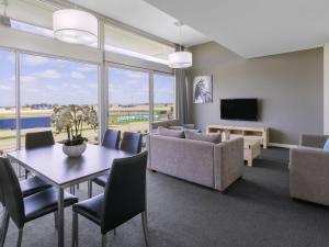 - un salon avec une table, un canapé et une télévision dans l'établissement Mantra Melbourne Melton, à Melton