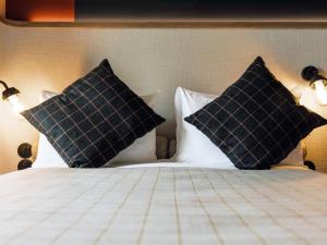 a bed with two black pillows on it at ibis Styles La Rochelle Centre Gare in La Rochelle +155 photos