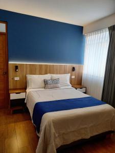 a bedroom with a large bed with a blue wall at Majhu Hostal in Tacna