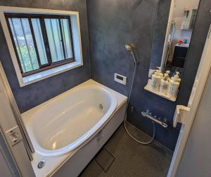 une salle de bain avec baignoire et douche avec fenêtre dans l'établissement Villa Mountainman - Vacation STAY 69075v, à Ichijuku