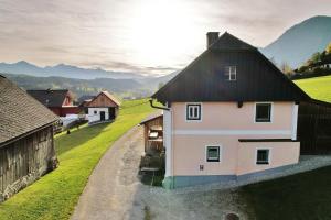 a white house with a black roof on a green field at Ferienhaus Schwöllerbauer in Sankt Martin am Grimming