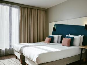 une chambre d'hôtel avec deux lits et une tête de lit bleue dans l'établissement Aparthotel Adagio Glasgow Central, à Glasgow
