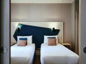 duas camas num quarto com uma cabeceira azul em Aparthotel Adagio Glasgow Central em Glasgow mais 67 fotografias