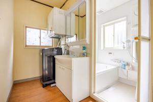 a kitchen with white cabinets and a sink and a tub at Umi to Neko - Vacation STAY 20484 in Hasaki +5 photos